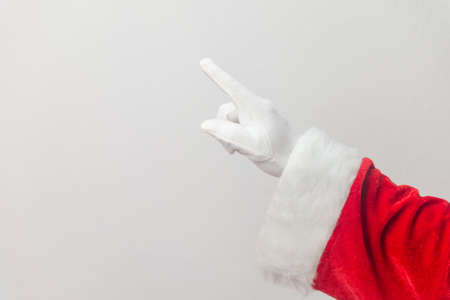 Santa Claus pointing finger show direction on a light texture background. Seasonal closeup of holiday excitement and hopeの写真素材