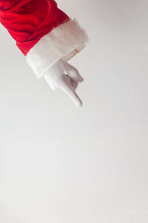 Santa Claus pointing finger show direction on a light texture background. Seasonal closeup of holiday excitement and hopeの写真素材