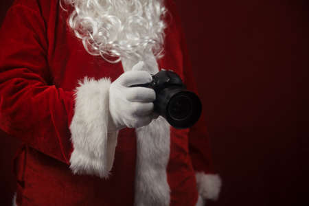 Santa Claus using holding in hands DSLR camera. Christmas and New Year celebration backgroundの写真素材