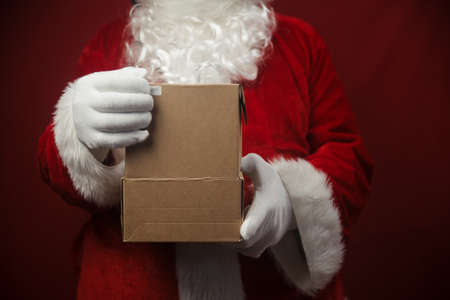 Father Santa Claus holding in hands surprise present gift box seasonal tradition background. Merry Christmas and Happy New Year amazing excitement joyful time!の写真素材