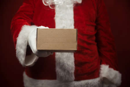Father Santa Claus holding in hands surprise present gift box seasonal tradition background. Merry Christmas and Happy New Year amazing excitement joyful time!の写真素材