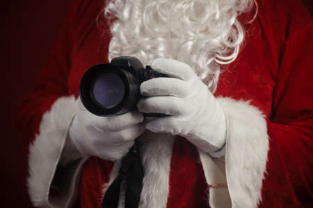 Santa Claus using holding in hands DSLR camera. Christmas and New Year celebration backgroundの写真素材