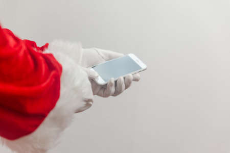Santa Claus using mobile phone modern smartphone communication technology background. Closeup mock up view. Business service solution and traditional holidaysの写真素材