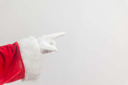 Santa Claus pointing finger. Direct approval guide trend. Closeup view of father xmas gloved hand in red costume show gesturing on white space backgroundの写真素材