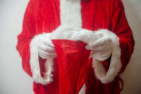 Santa Claus holding in hands red hat on white seasonal background. Ready for festive time. Merry Christmas and Happy New Year close up photographyの写真素材