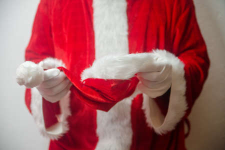 Santa Claus holding in hands red hat on white seasonal background. Ready for festive time. Merry Christmas and Happy New Year close up photographyの写真素材