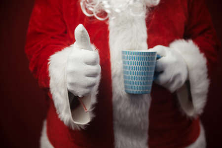 Relaxing Santa Claus drinking holding hot mug, festive leisure lifestyle closeup image. Merry Christmas and Happy New Year amazing excitement joyful seasonal holidays time!の写真素材
