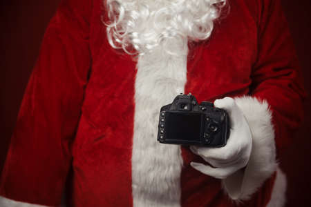 Santa Claus using holding in hands DSLR camera. Christmas and New Year celebration backgroundの写真素材