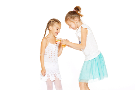 Beautiful little girls in white dress eating jellyの写真素材
