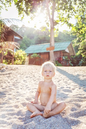 Little angel sitting on a white sand beach in Thailandの写真素材