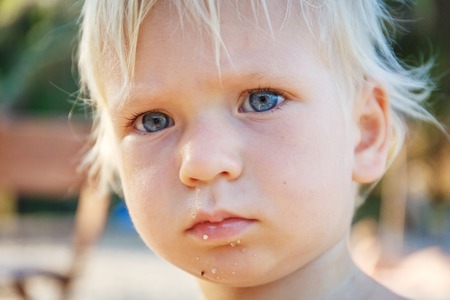 Baby with blond hair and blue eyes on the beachの写真素材