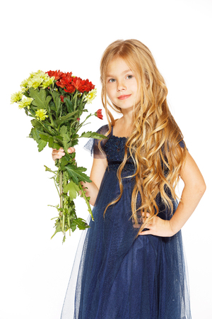 Charming little girl with curly hair in a blue dress with a bouquet of flowersの写真素材