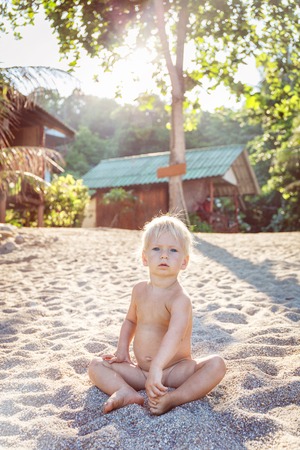 Little angel sitting on a white sand beach in Thailandの写真素材