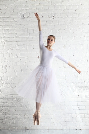 Young ballerina and the white brick wall backgroundの写真素材