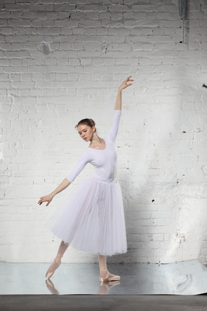 Young ballerina and the white brick wall backgroundの写真素材