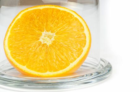 Slice a fresh juicy  round orange in a transparent glass bowl isolated on whiteの写真素材