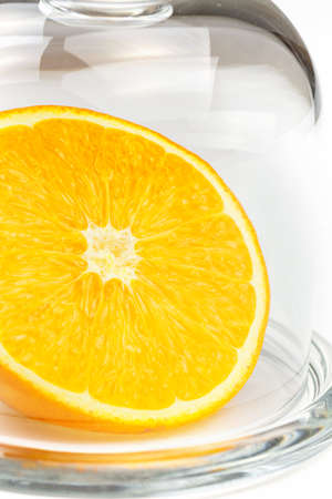 Slice a fresh juicy  round orange in a transparent glass bowl isolated on whiteの写真素材