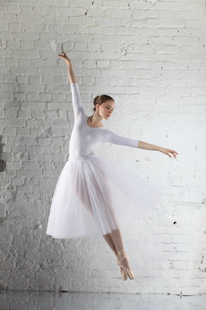 Young ballerina and the white brick wall backgroundの写真素材