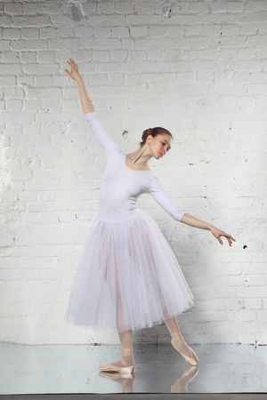 Young ballerina and the white brick wall backgroundの写真素材