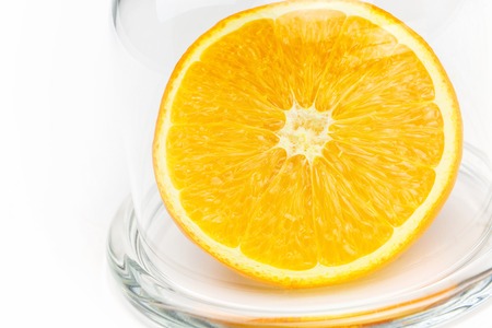 Slice a fresh juicy  round orange in a transparent glass bowl isolated on whiteの写真素材