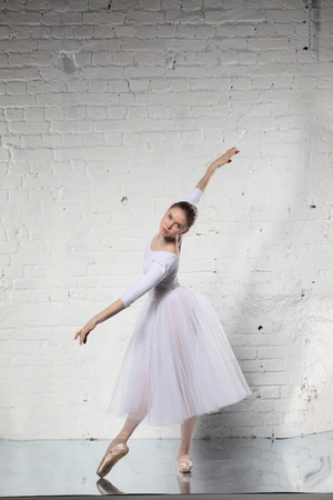 Young ballerina and the white brick wall backgroundの写真素材