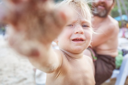 Baby on the beach of Thailand throws at the camera beach sandの写真素材