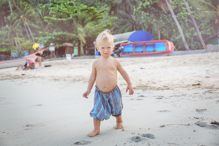 Little boy walking barefoot on white sand beachの写真素材