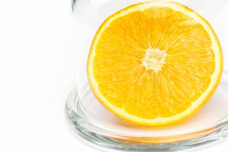 Slice a fresh juicy  round orange in a transparent glass bowl isolated on whiteの写真素材