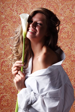 Pretty smiling girl in a white shirt with a flowerの写真素材