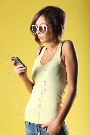 Beautiful girl on yellow background with sunglassesの写真素材