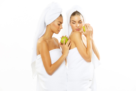 Two happy teen girl after shower playing with an appleの写真素材