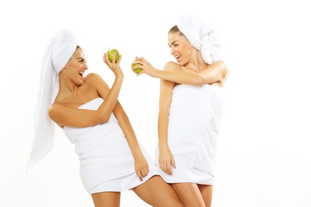 Two happy teen girl after shower playing with an appleの写真素材