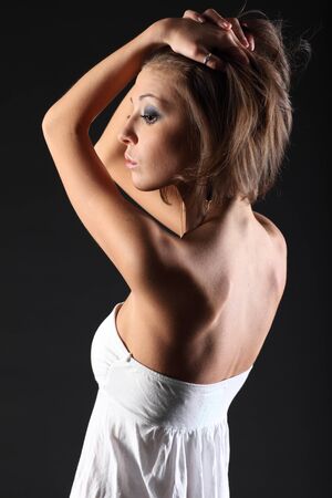 Beautiful girl on black background in white dressの写真素材