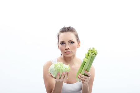 Girl holding a green cabbage and celery isolated on whiteの写真素材