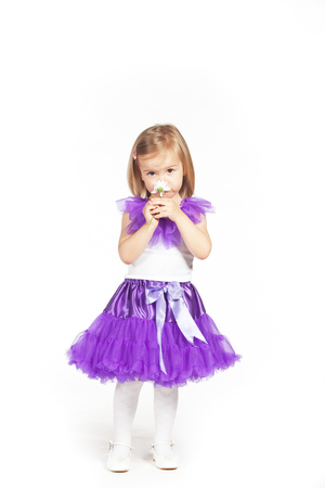 Little girl in a purple skirt with flower in handの写真素材