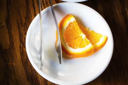 Sliced fresh orange on a white plate on a wooden tableの写真素材