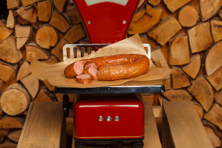Sausage on red scales on wooden backgroundの写真素材