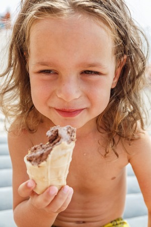 Little boy eating an ice cream on the beachの写真素材