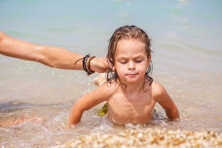 Tanned long-haired boy on the rocky shoreの写真素材