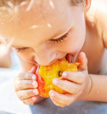 Boy eating a peachの写真素材
