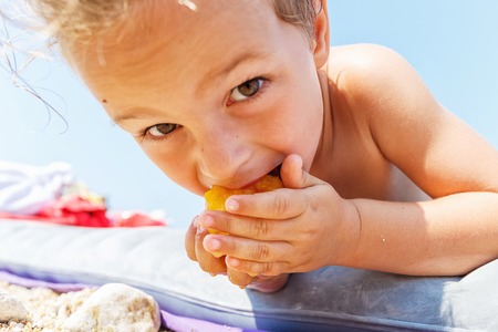 Boy eating a peachの写真素材