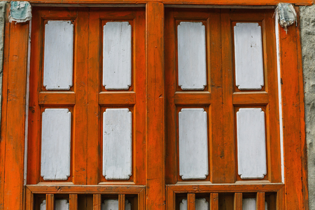 Old textured wooden brown shutters on the stone wallの写真素材