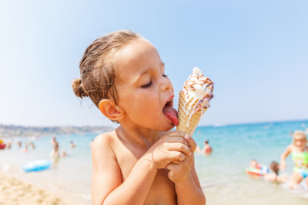 Beautiful boy is eating an ice cream on the beachの写真素材