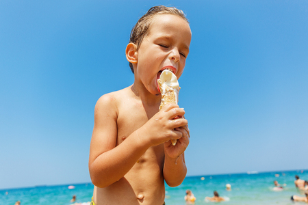 Beautiful boy is eating an ice cream on the beachの写真素材