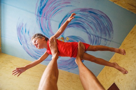 Flying boy like super hero on the blue ceiling backgroundの写真素材