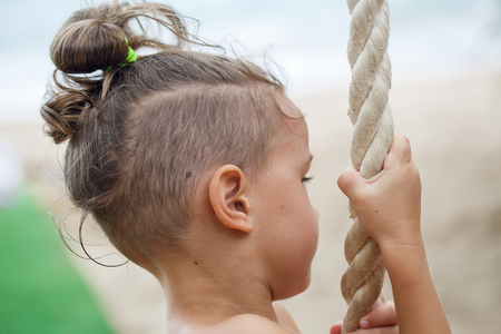 Little boy climbing a rope on the beachの写真素材
