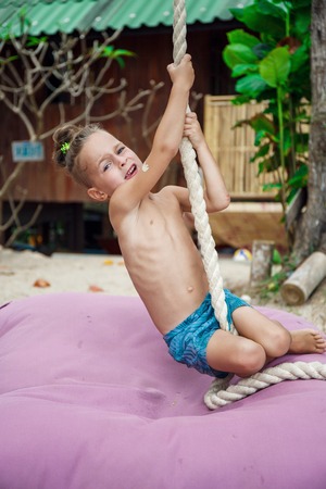 Little boy climbing a rope on the beachの写真素材