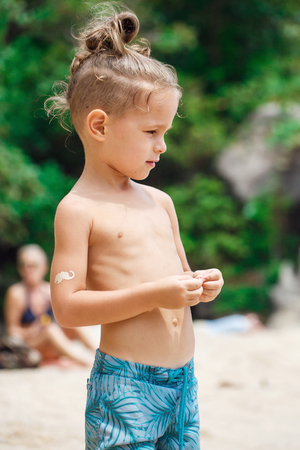 little serious boy standing on the beachの写真素材