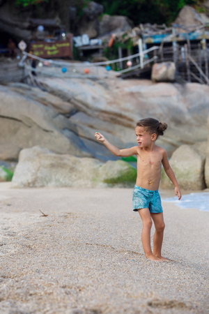 boy standing on the sand by the seaの写真素材