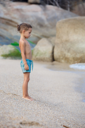 boy standing on the sand by the seaの写真素材